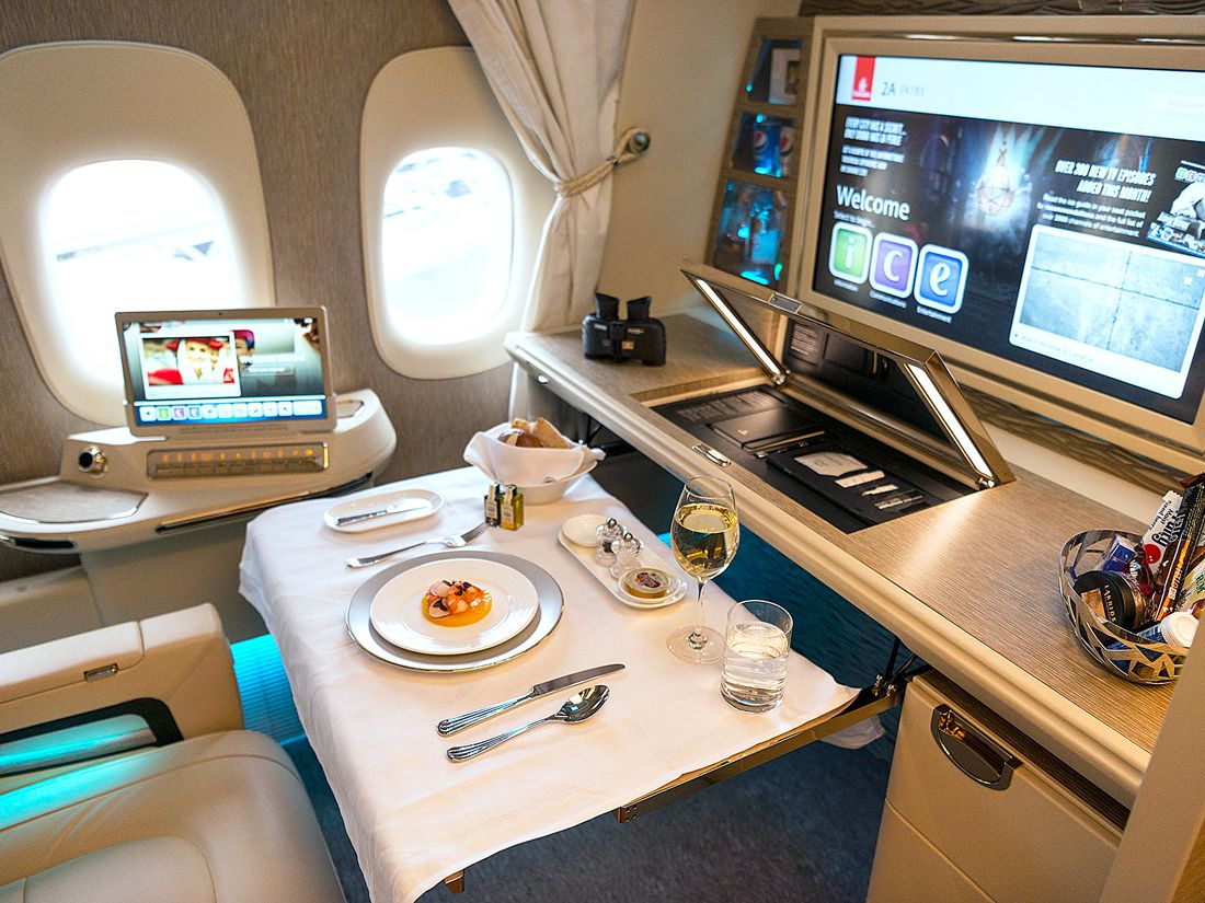 Emirates First Class suite with plated meal and large entertainment screen