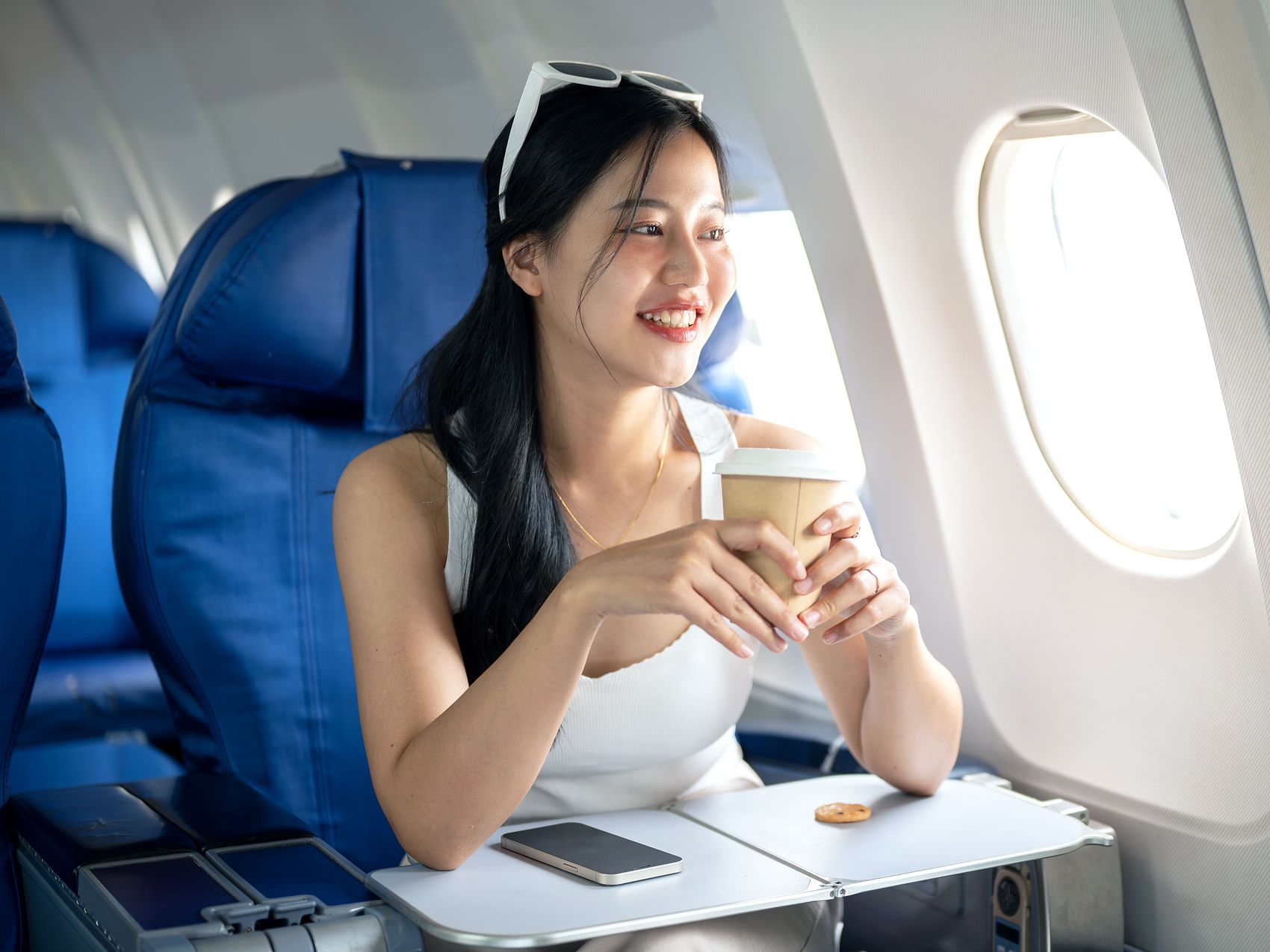 Passenger wearing tank top and holding coffee cup on airplane