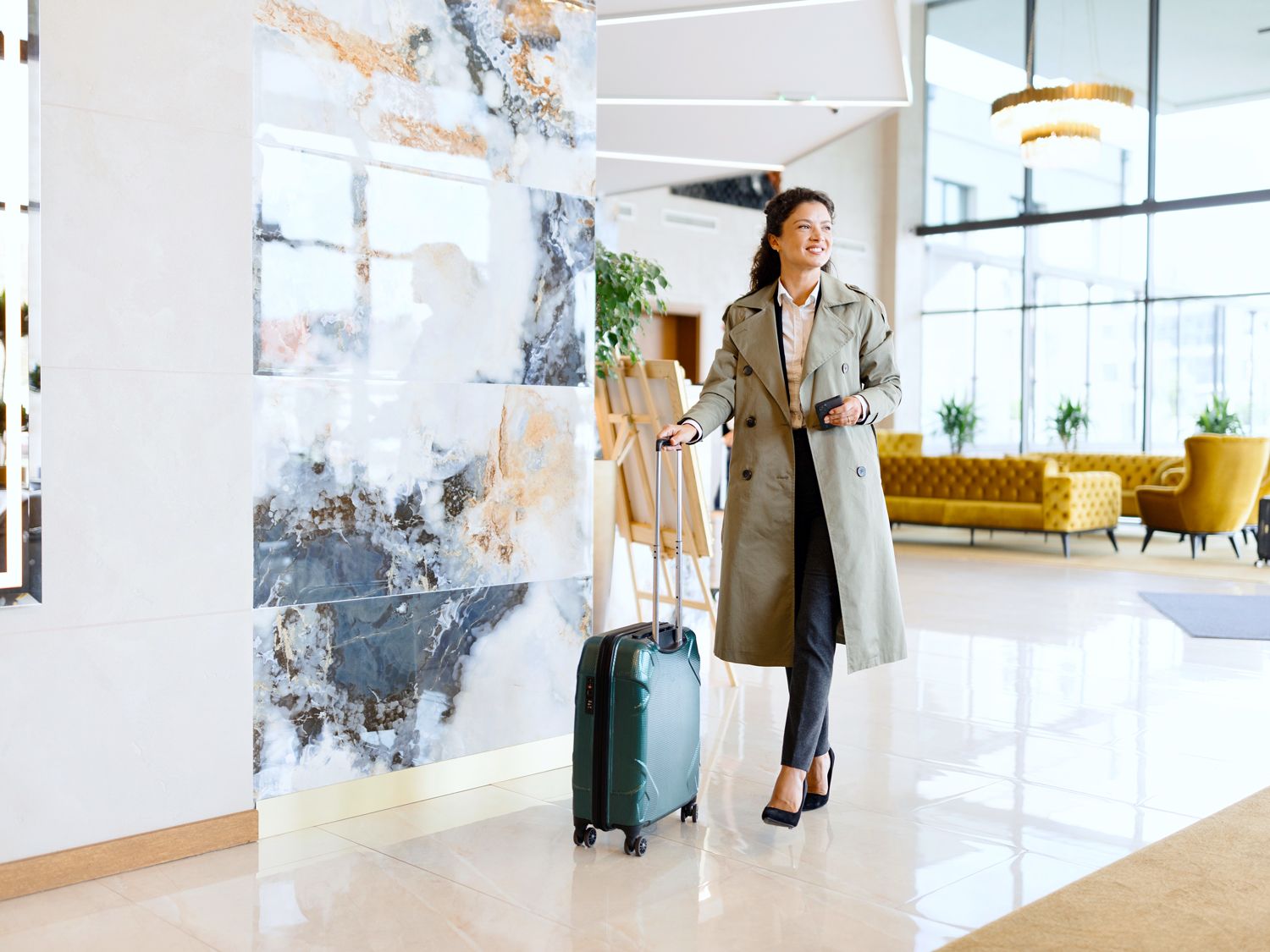 Hotel guest rolling suitcase through lobby