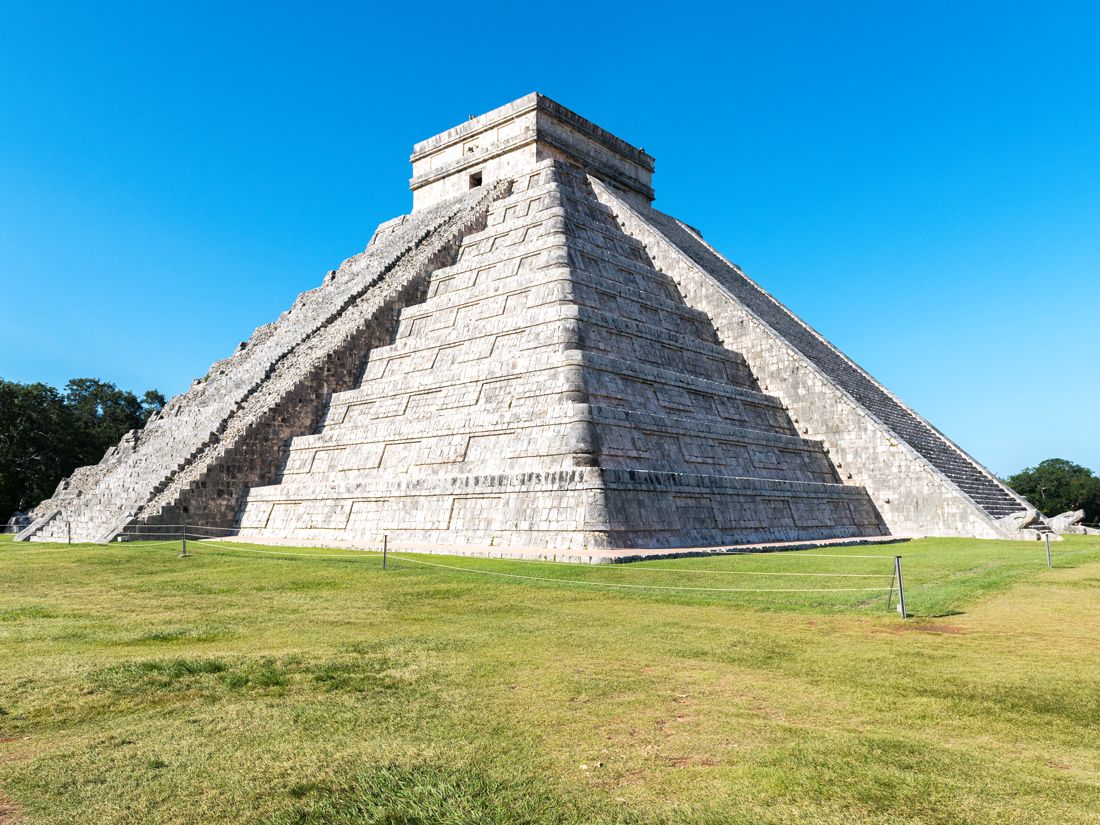 Temple of Kukulcán standing in grassy field in Chichén Itzá, Mexico