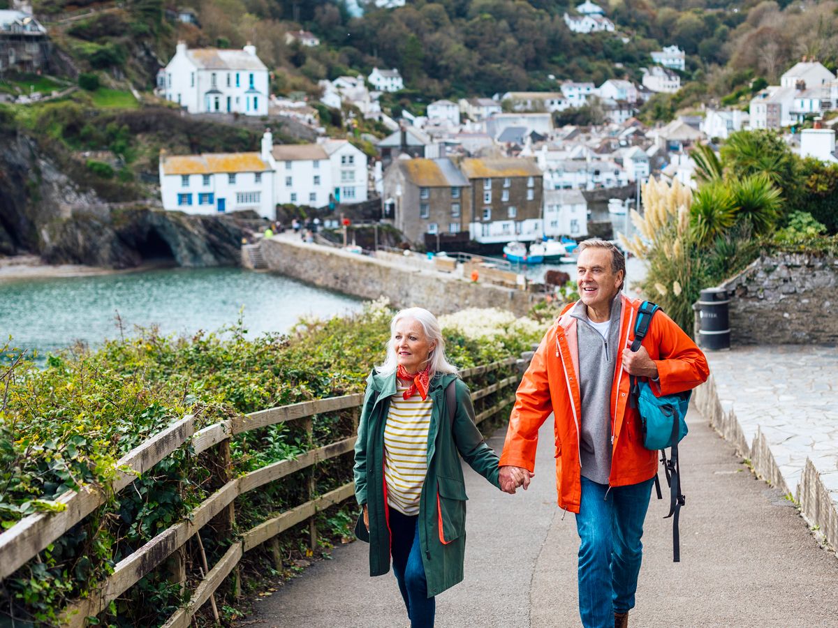 Older couple holding hands walking through waterfront village