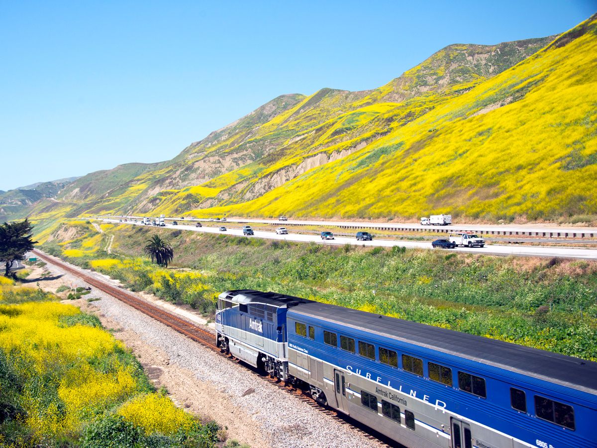 Amtrak Pacific Surfliner train alongside motorway and mountains