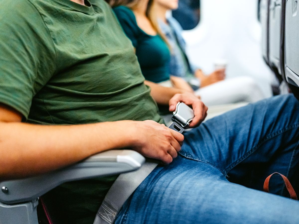 Close-up of airline passenger fastening seatbelt