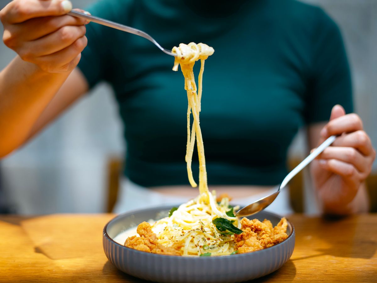 Person eating a plate of pasta
