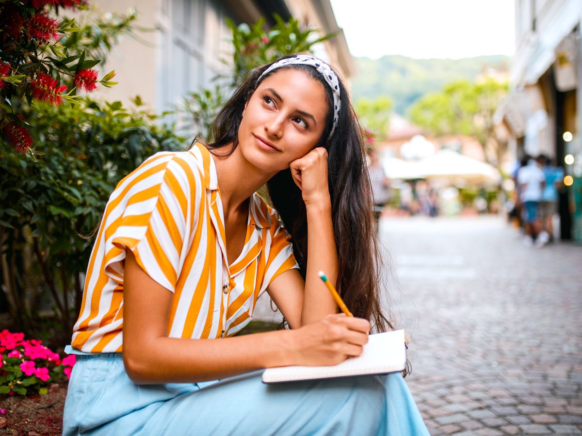 Woman sitting on street writing in journal