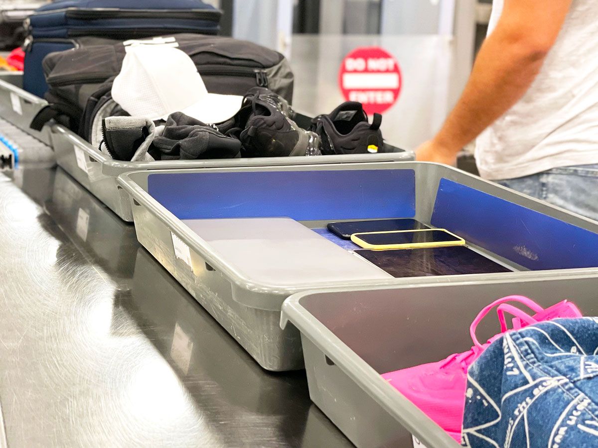Items in bins on airport security conveyor belt at screening checkpoint