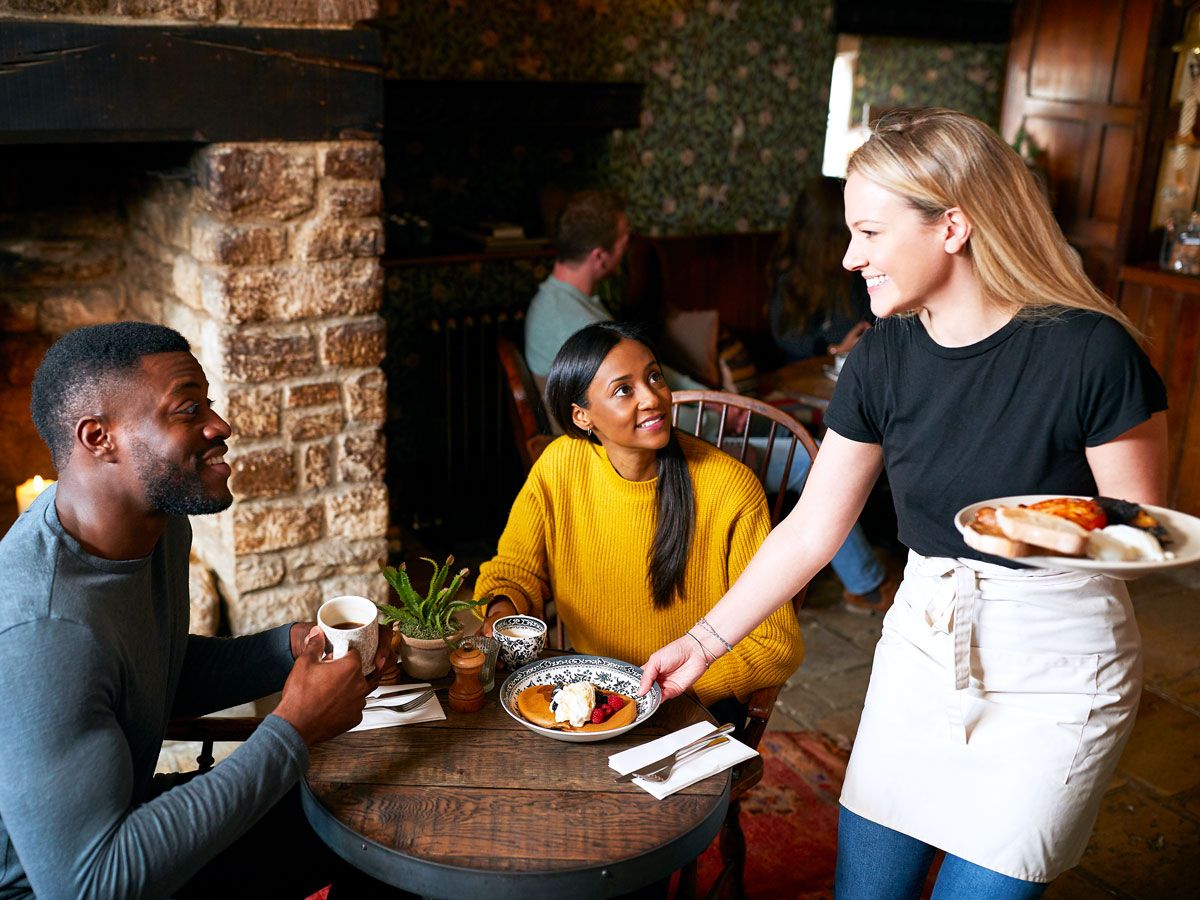 Waitress serving food to couple dining