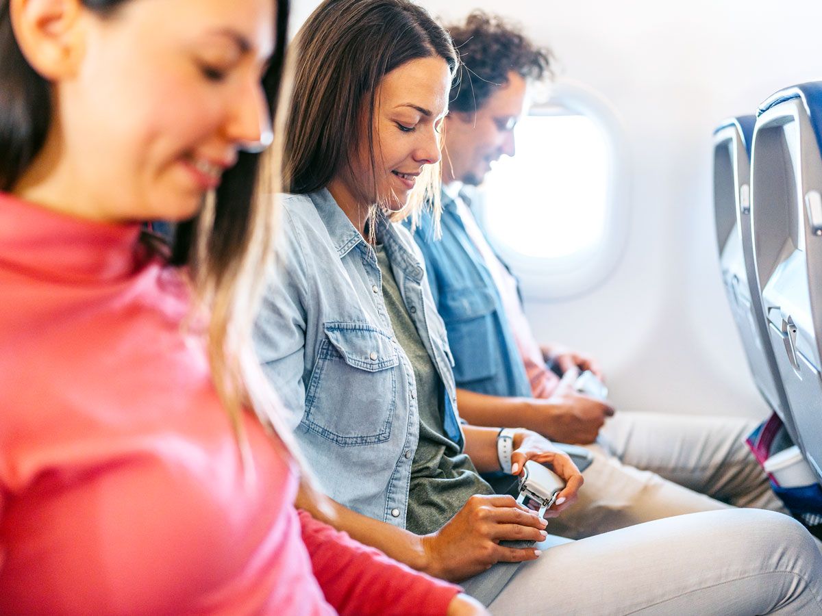 Passengers on plane fastening their seat belts