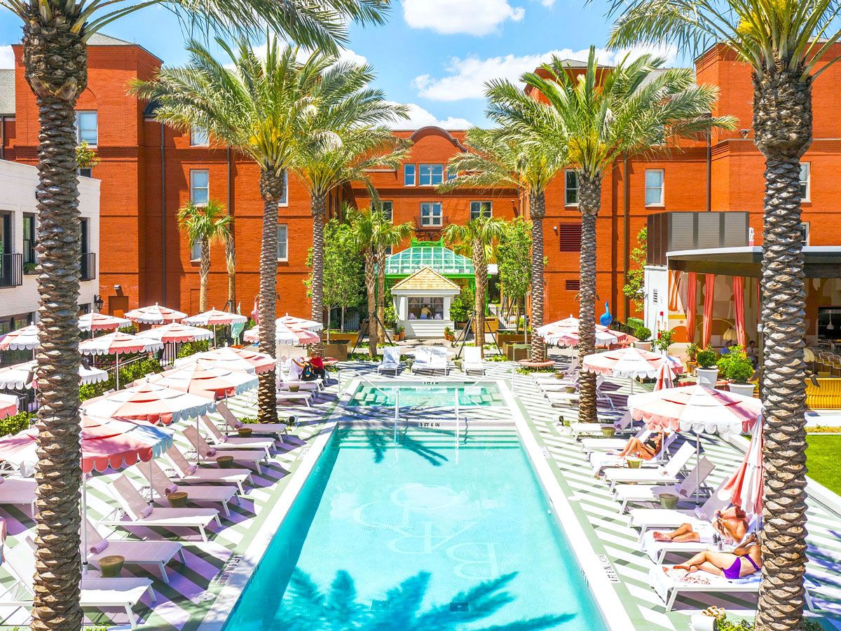 Chairs, umbrellas, and palm trees lining pool at Hotel Bardo in Savannah, Georgia