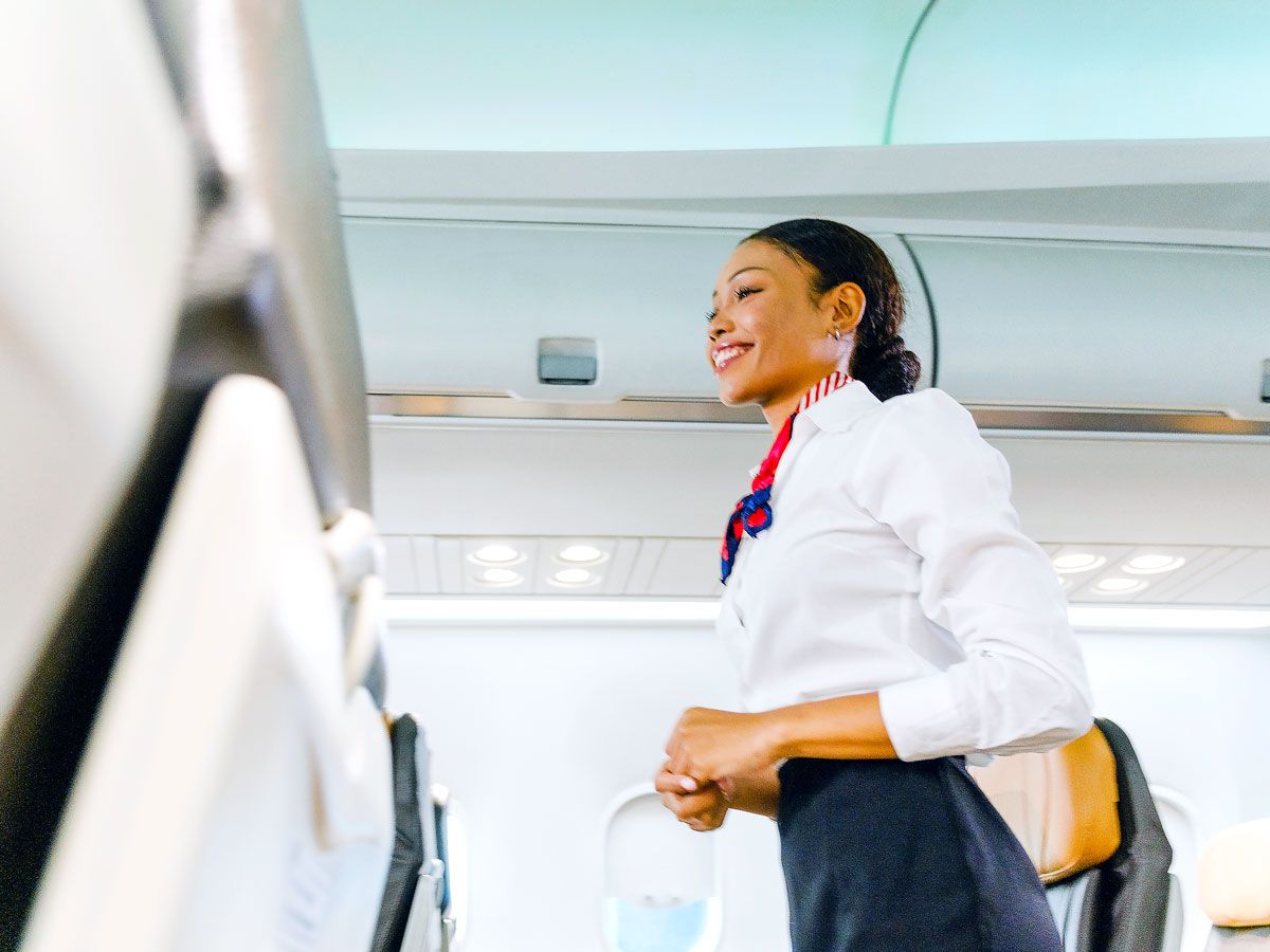 Flight attendant walking through aircraft aisle