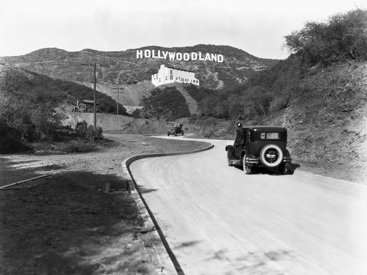 Cars driving toward "Hollywoodland" sign circa 1924