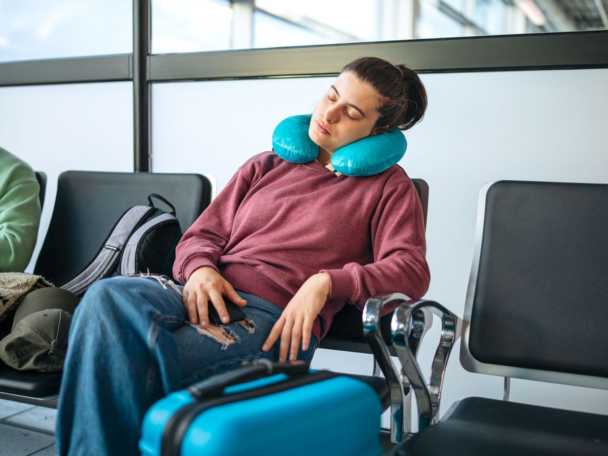 Traveler sleeping with neck pillow in airport terminal