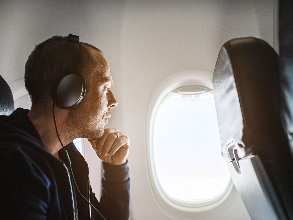 Passenger wearing headphones and gazing out airplane window