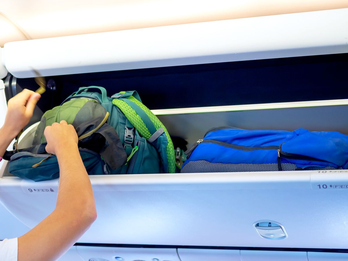 Traveler stowing bags in aircraft's overhead bin