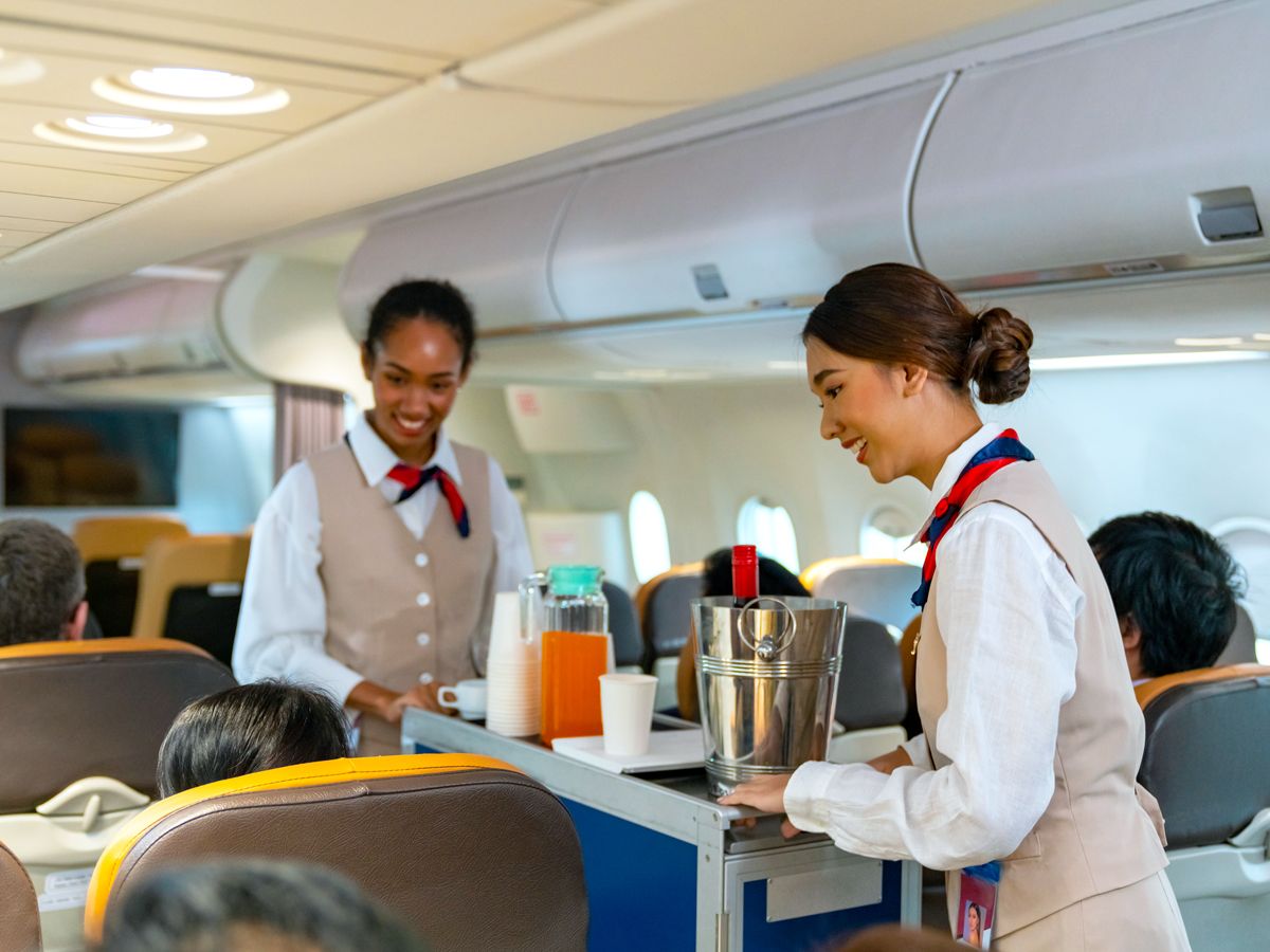 Flight attendants performing beverage service in flight