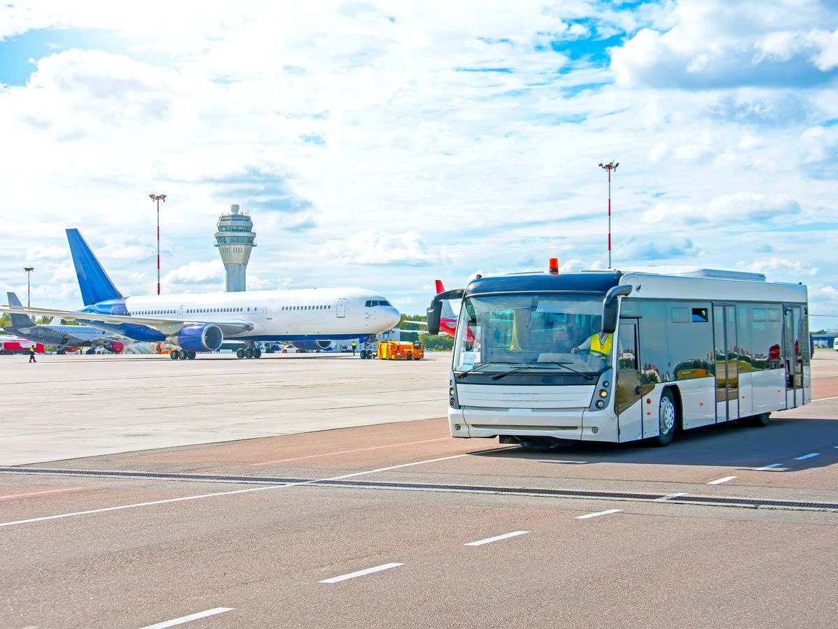 Bus taking passengers across airport tarmac to board plane via air stairs