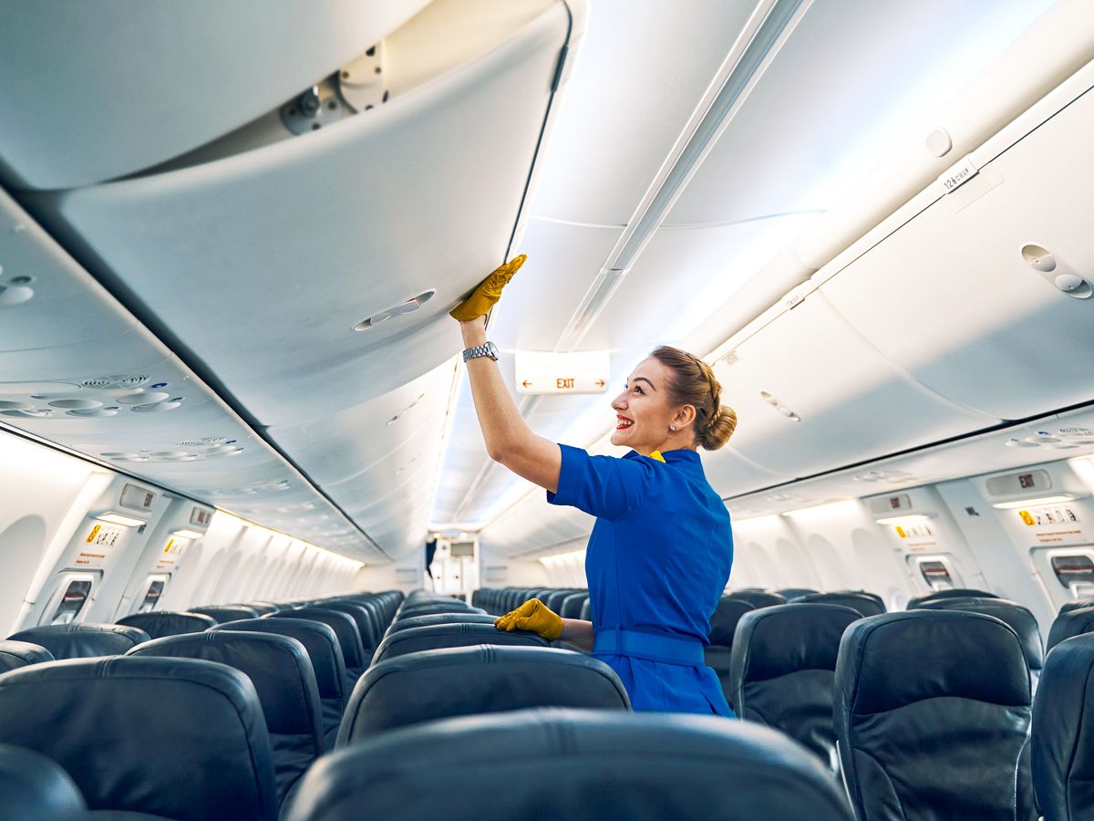 Flight attendant closing aircraft overhead bin