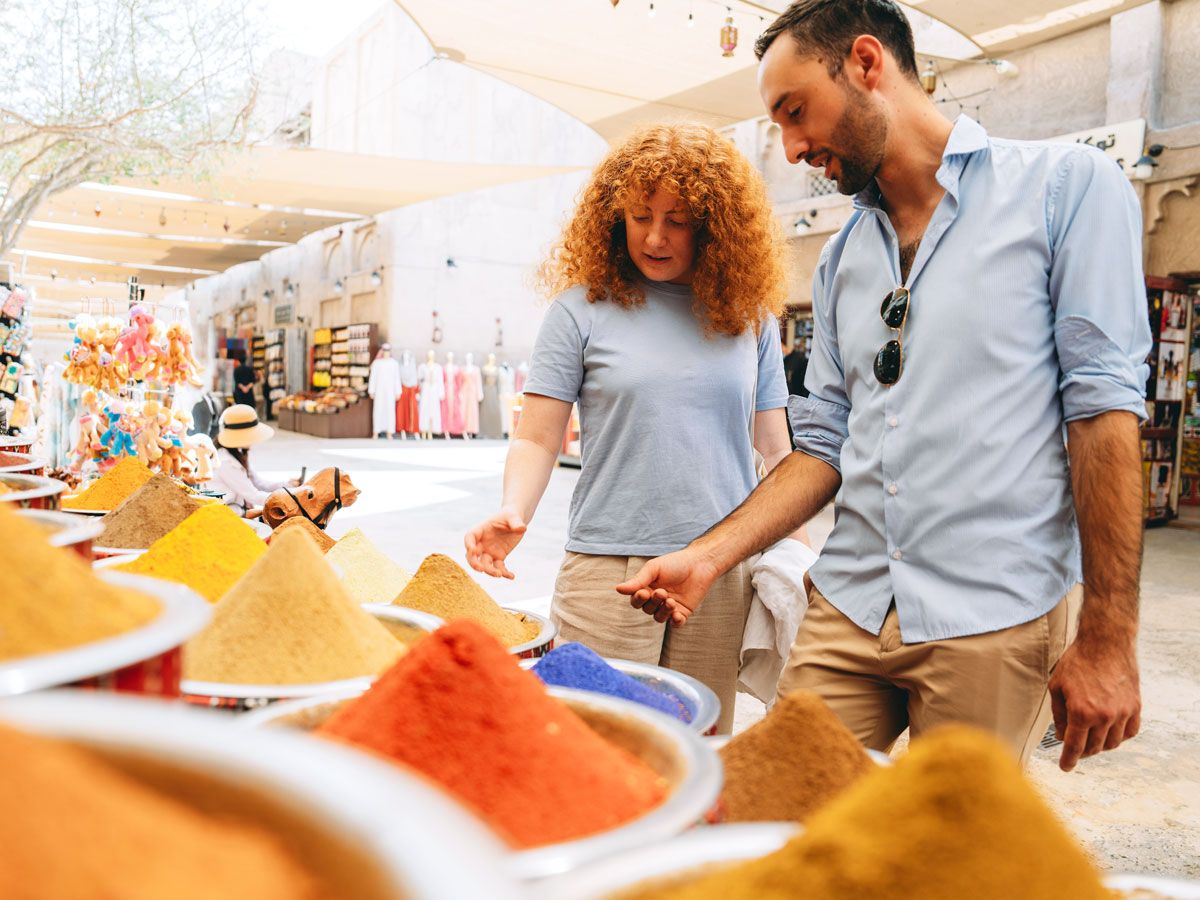 Travelers shopping for spices at outdoor market stall