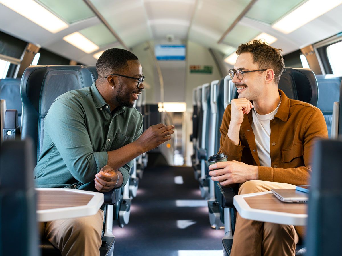 Two people conversing across train aisle