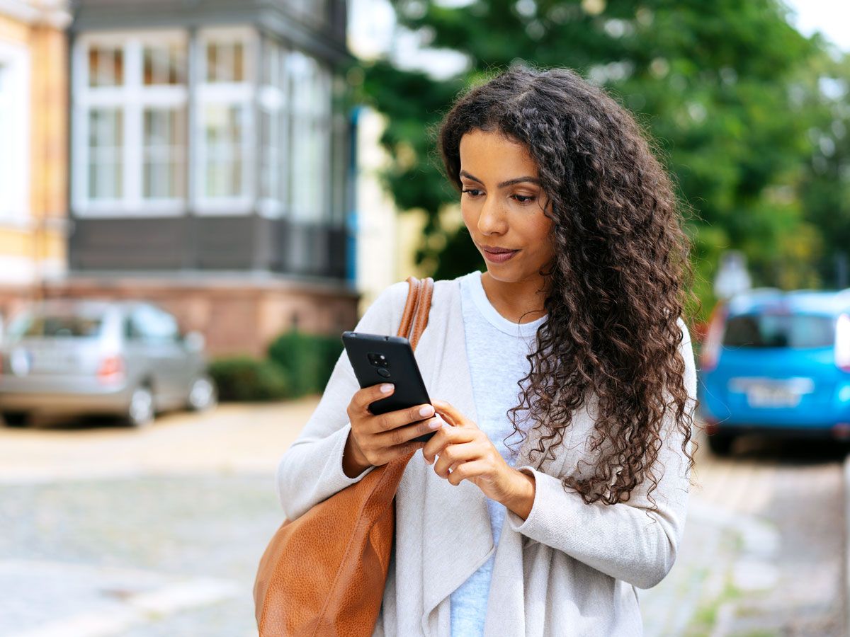 Woman standing on street looking at phone