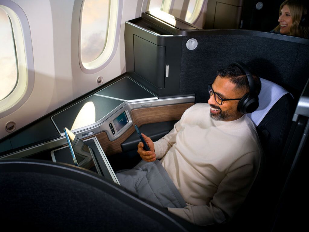 Passenger using phone and laptop in business-class seat