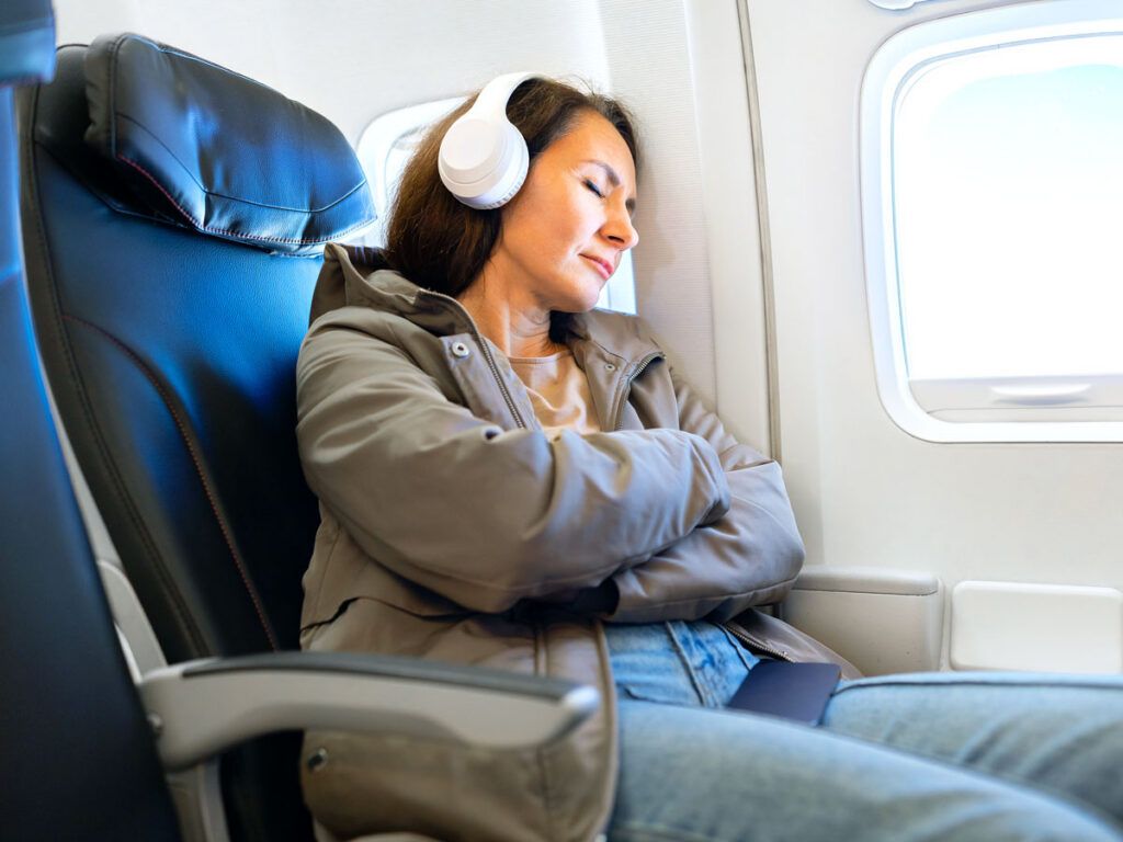 Passenger wearing headphones in seat leaning against window