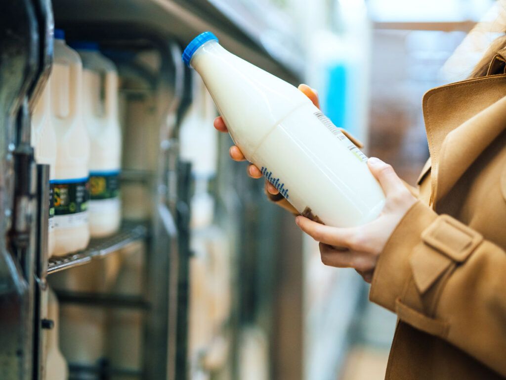 Shopper holding milk jug in grocery store