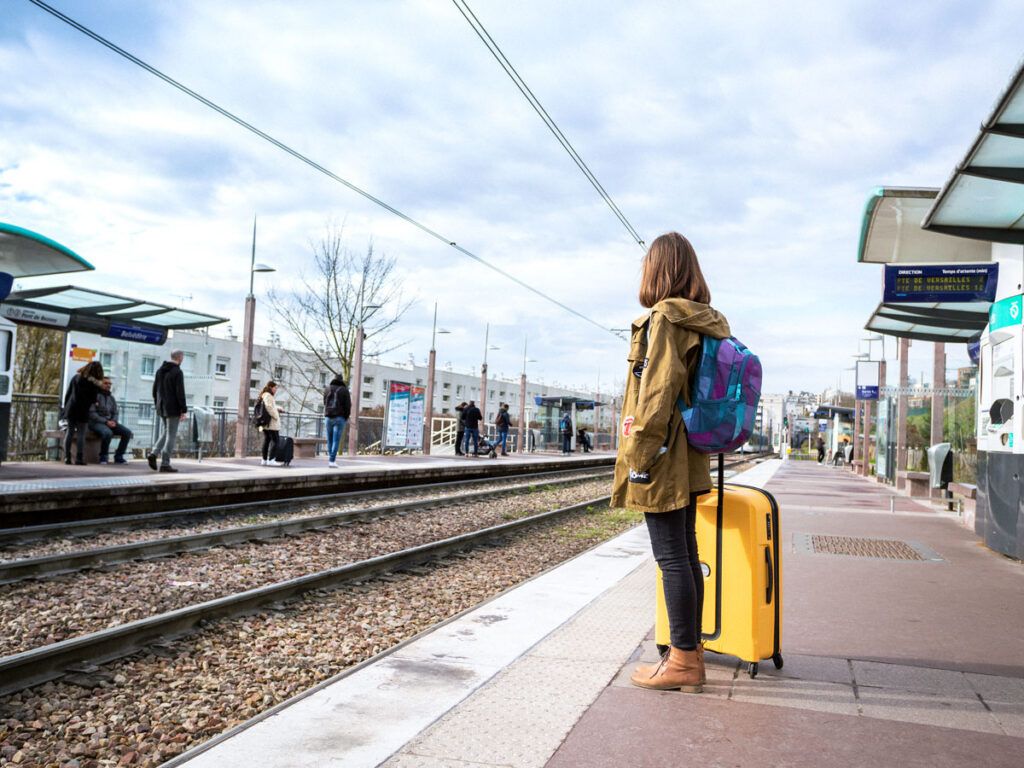 Person waiting on train platform with luggage