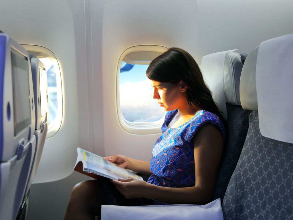 Passenger reading magazine in window seat