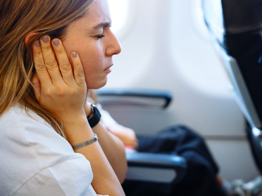 Airline passenger holding hands over her ears