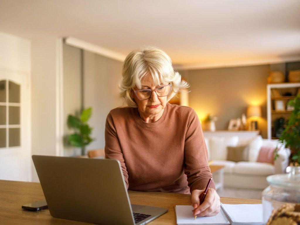 Woman working at desk with laptop and notepad