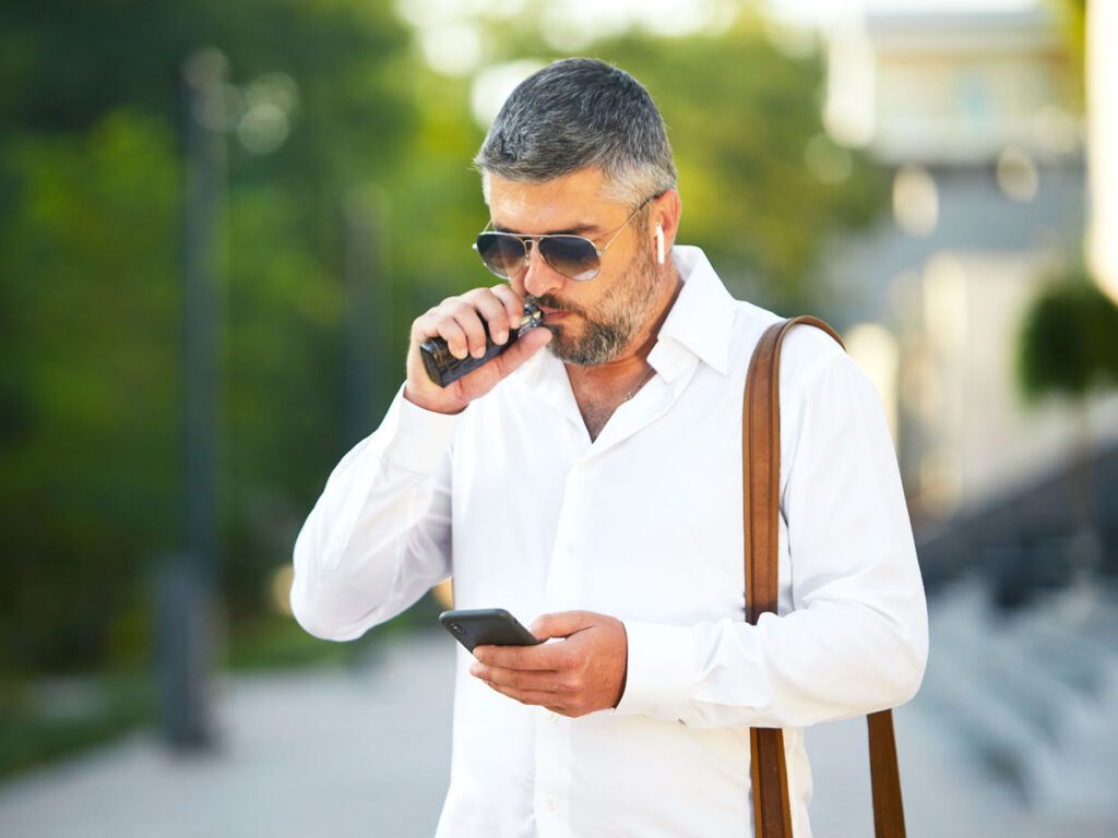Man vaping while looking at cellphone