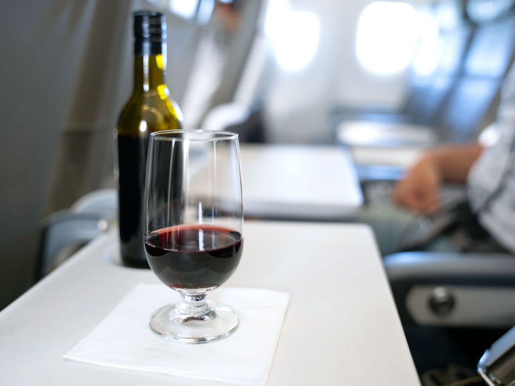 Airline passenger with glass and bottle of wine on tray table