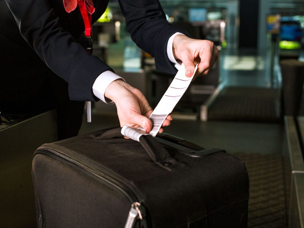 Agent securing bag tag to luggage handle