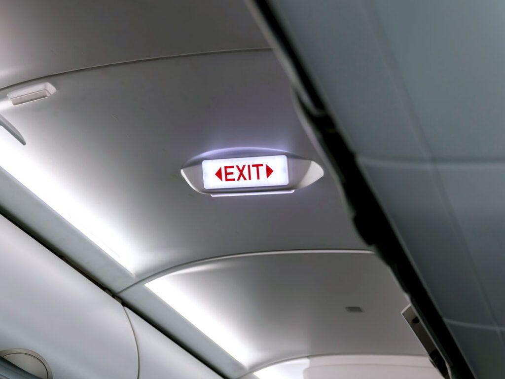 Illuminated exit sign on airplane ceiling