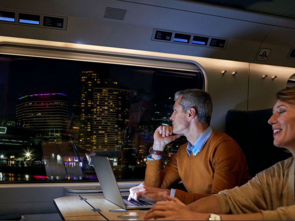 Amtrak rider looking out train window at city skyline lit during evening