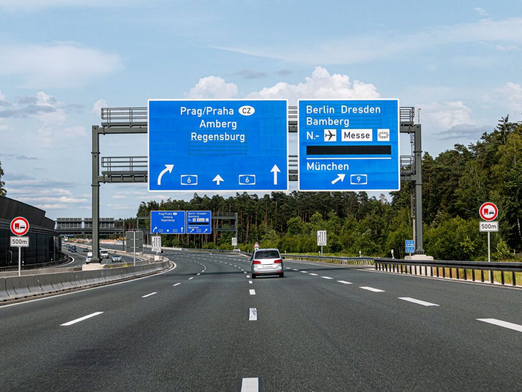 Car driving under road signs on Germany's Autobahn