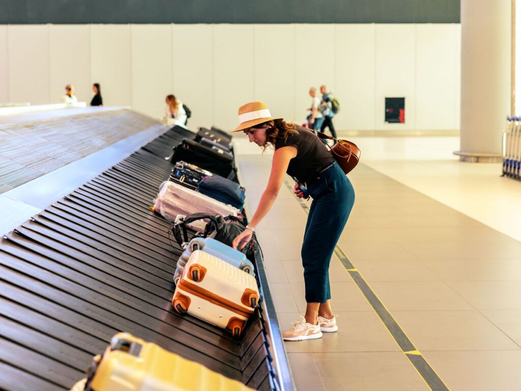 Passenger retrieving bag from carousel
