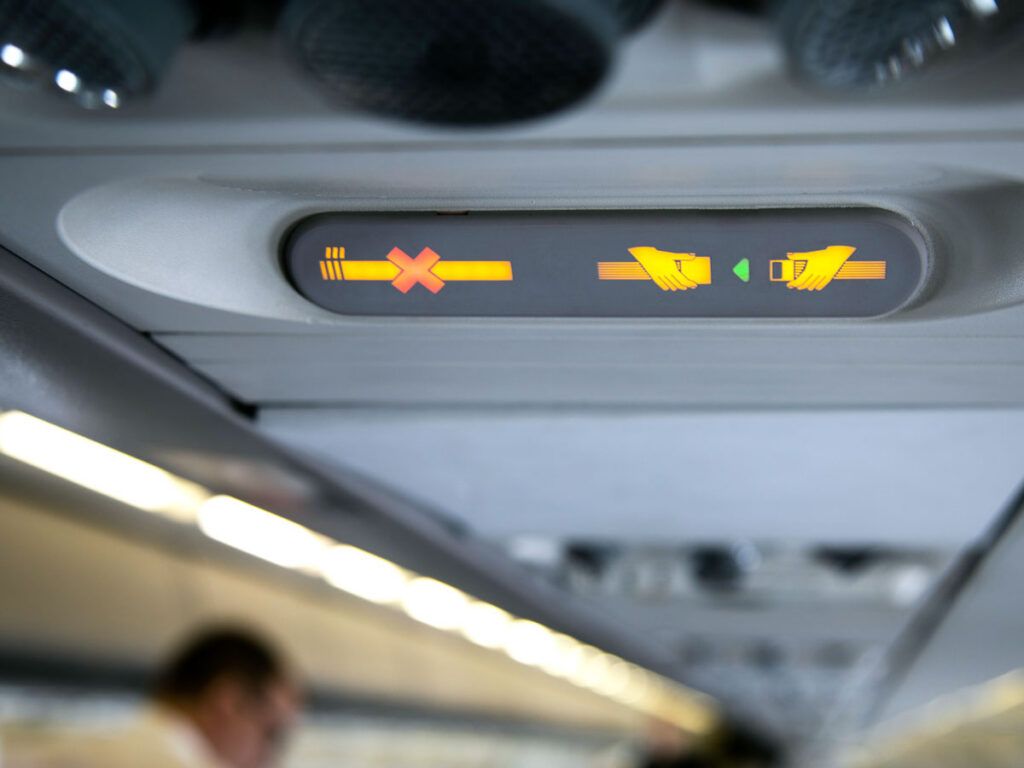 Close-up of 'no smoking' and 'fasten seatbelt' signs on airplane