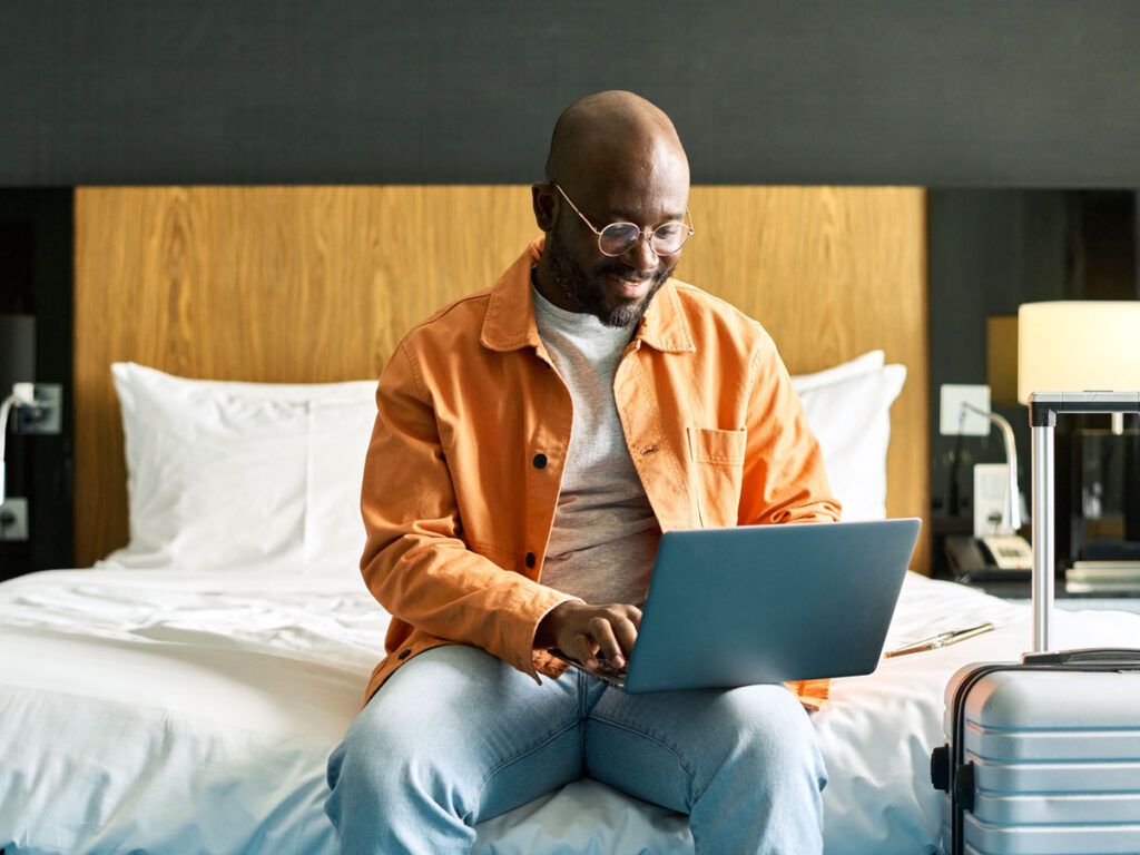 Hotel guest using laptop on bed