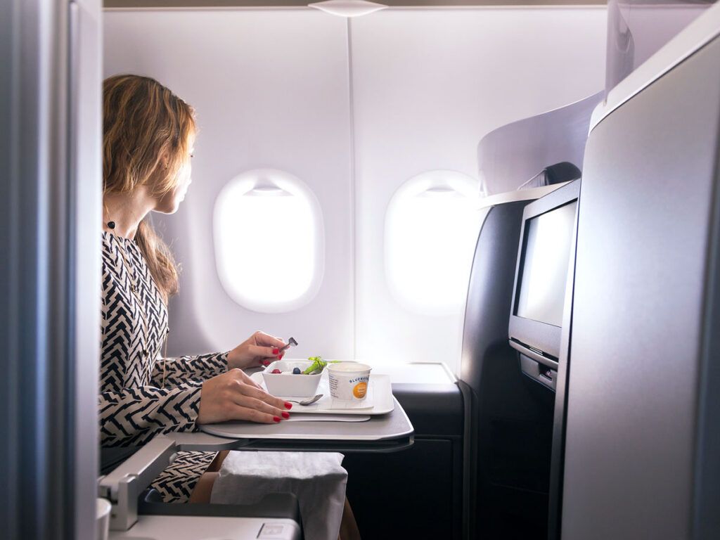 Passenger dining in business-class suite while looking out window