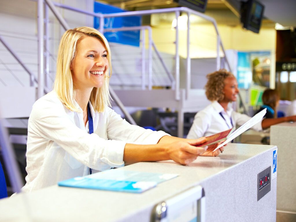 Airline employee handing boarding pass and passport to customer