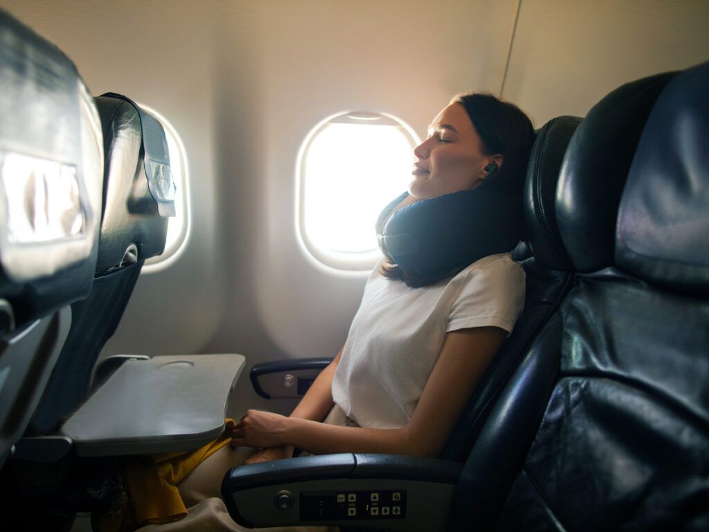 Traveler in window seat with neck pillow