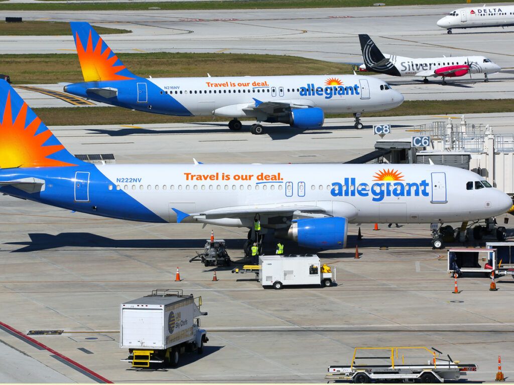 Allegiant plane parked at gate while another taxis past