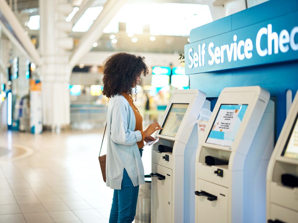 Passenger using self-service check-in kiosk at airport