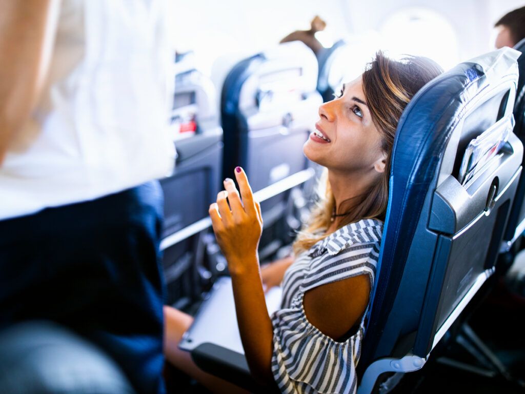 Passenger speaking to flight attendant in aisle
