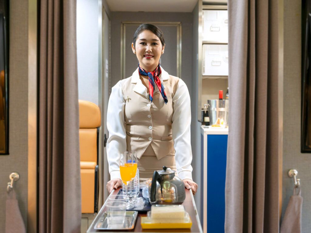 Flight attendant pushing cart through aisle