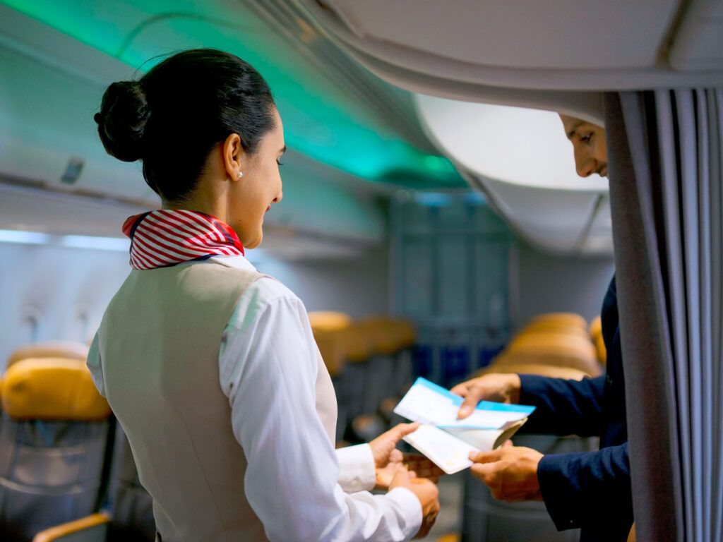 Flight attendant checking passenger's ticket at boarding door