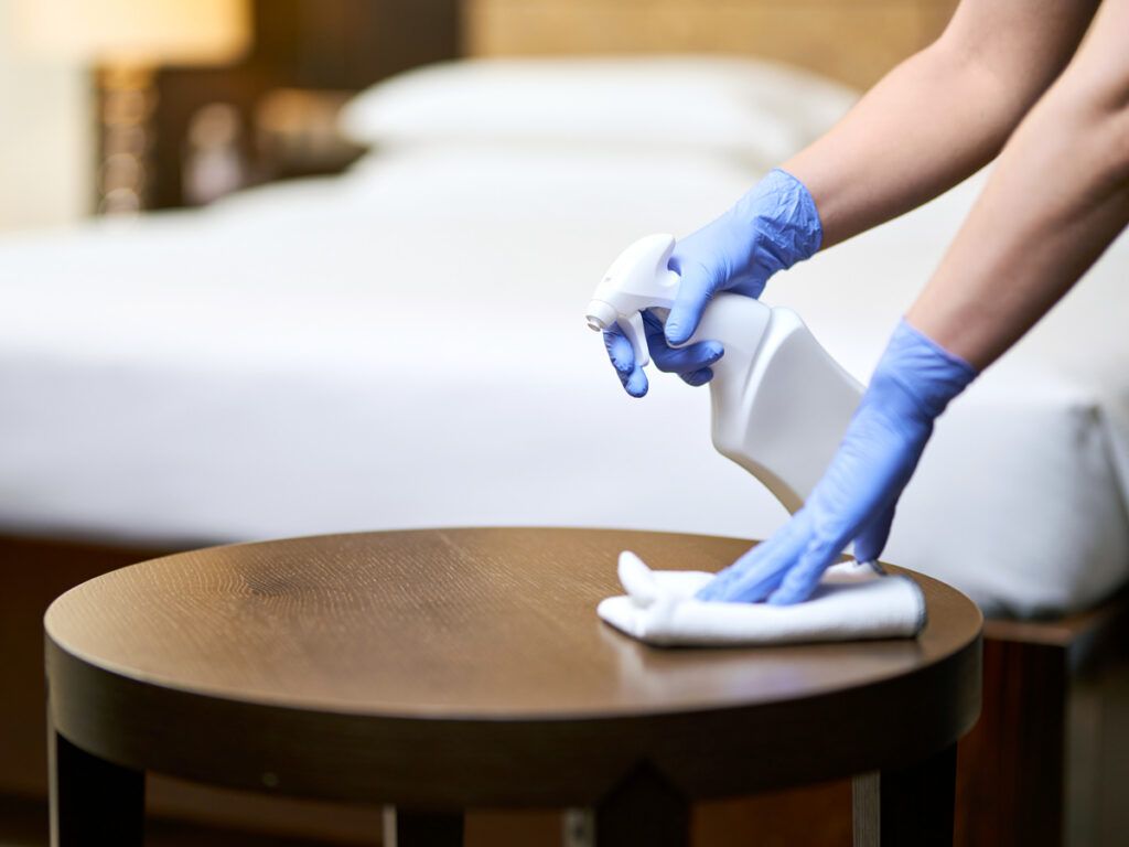 Housekeeper wiping table in hotel room