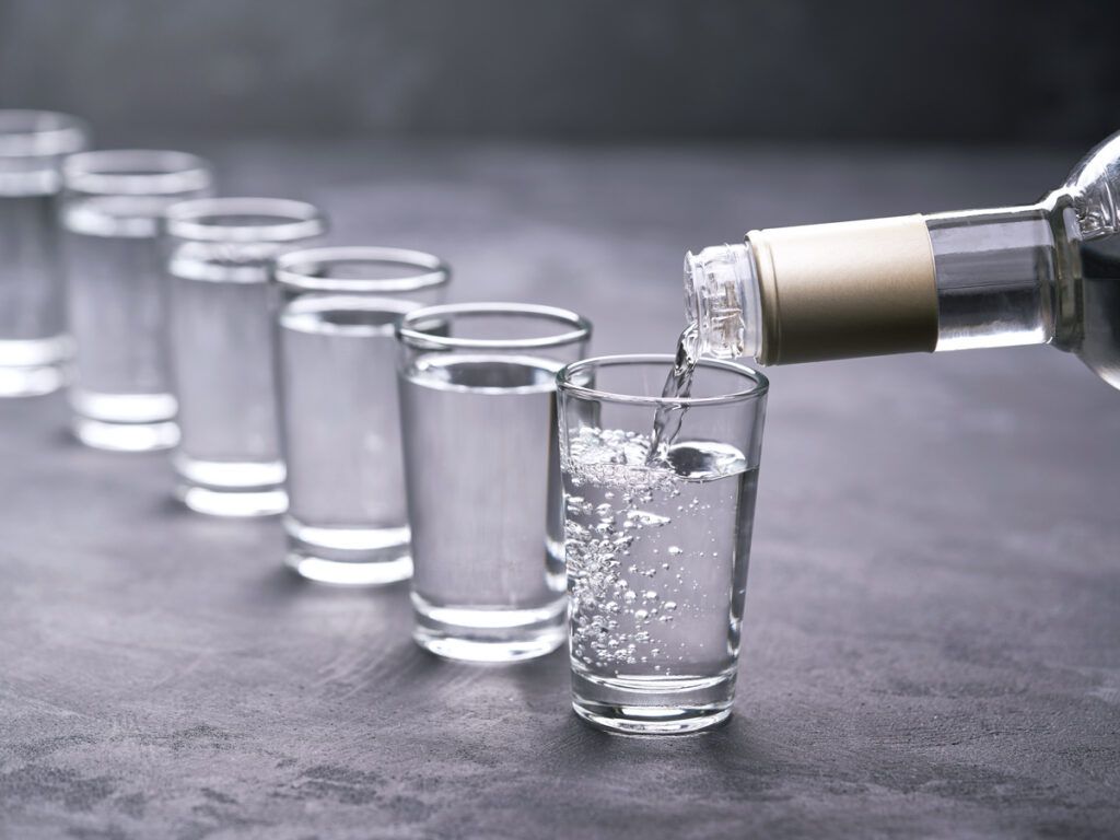 Person pouring shots of vodka